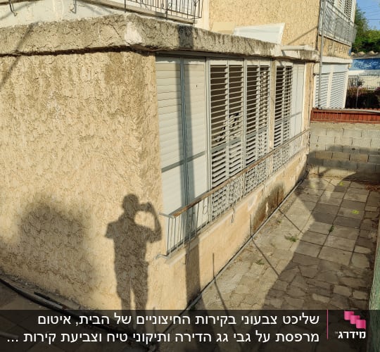 קיר חיצוני עם טיח מתקלף, צינור על הקרקע